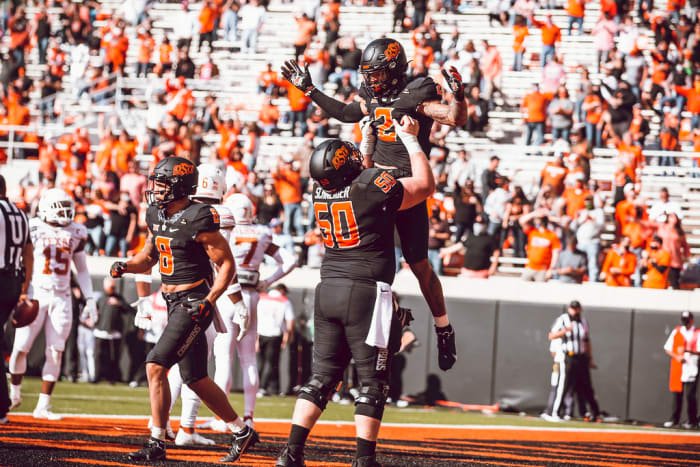 Oklahoma State center Ry Schneider lifts up wide receiver Tylan Wallace in celebration after a touchdown against Texas.